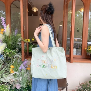 Détail du sac cabas en toile vert clair avec broderie Lucky Suzakka et motifs de graffiti
