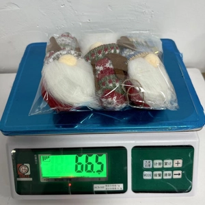 Three plush Christmas gnomes in polybag packaging weighed at 66.5g on a digital scale