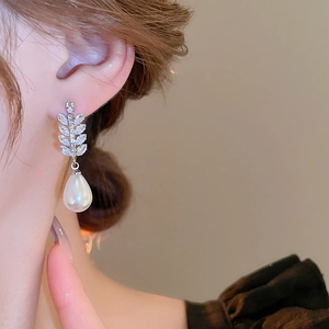 Detail of elegant leaf zircon earring with water drop pearl on a female model