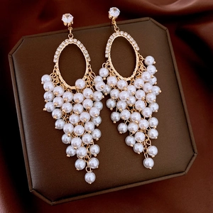 Detail of golden hoop earrings featuring cubic zirconia and cascading white pearl tassels