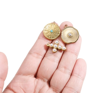 Handheld view of gold stainless steel cross and pearl pendants for jewelry making