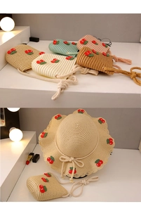 Close-up of kids straw sun hat with red knit cherry charms and matching mini shoulder bags