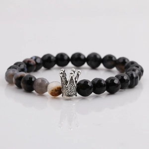 Macro shot of 8mm faceted black beads and vintage silver crown pendant on men's bracelet
