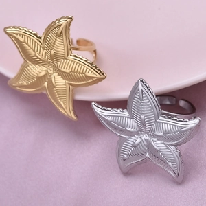 Close-up of gold and silver starfish-shaped 304 stainless steel adjustable rings on pink base