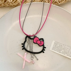 Detail of cartoon bow glass necklace with pink ribbon and bead charms on ceramic plate