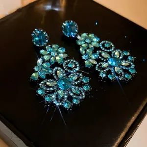 Exaggerated floral drop earrings with sea blue crystals and dark finish for gala events