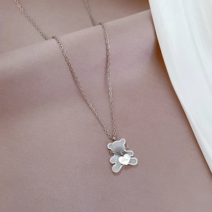 Detailed macro view of silver bear pendant with engraved heart love tag on fabric