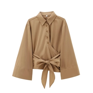 Détail d'une chemise en popeline kaki avec boutons dorés et lien de serrage à la taille