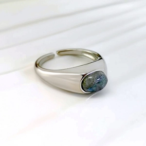 Retro silver adjustable ring with oval labradorite stone on white striped background
