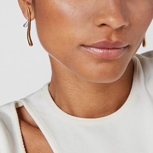 Gros plan de boucles d'oreilles dorées ondulées portées par un mannequin avec élégance