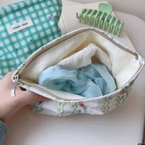 Detail of green plaid and floral canvas cosmetic bags showing inner lining and zipper