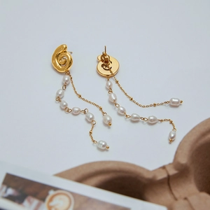 Close-up of gold spiral metal tassels with multiple white pearls on luxury earrings
