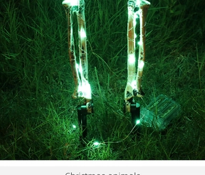 Outdoor Halloween skeletal stakes with green LED lights on a nighttime garden lawn