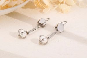 Detailed close-up of long pearl drop earrings in silver finish with metal frames