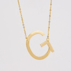 Détail macro d'un collier en acier inoxydable doré 18K avec pendentif lettre G