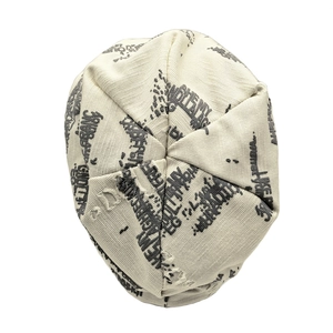 Detail of ripped beige knit beanie showing grey letter print and distressed texture