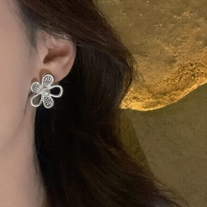 Detailed close-up of hollow flower pearl stud earring worn on ear with silver finish