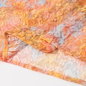 Detailed macro view of orange and yellow lace fabric with intricate mesh texture and stitching