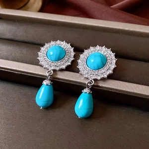 Macro detail of sunflower turquoise earrings with rhinestones and teardrop pendant