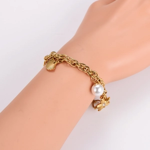 Ocean style gold pearl bracelet featuring starfish and shell charms on model wrist