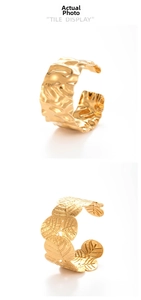 Detail showing irregular hammered texture and leaf patterns on wide gold stainless steel cuff