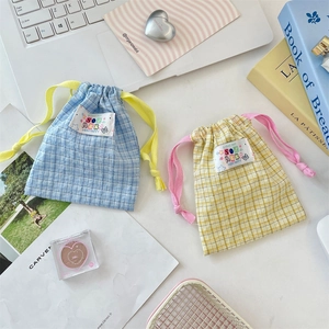 Detail of blue and yellow plaid drawstring storage bags with cartoon labels on a desk