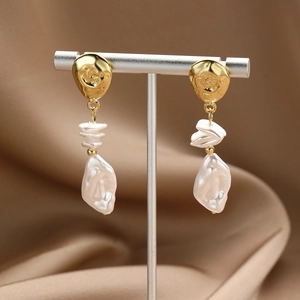 Detail of gold irregular textured earrings with baroque pearls on a silk background