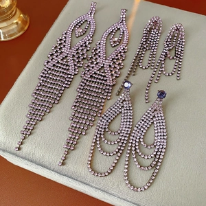 Detailed macro view of three pairs of purple rhinestone fringe and geometric drop earrings
