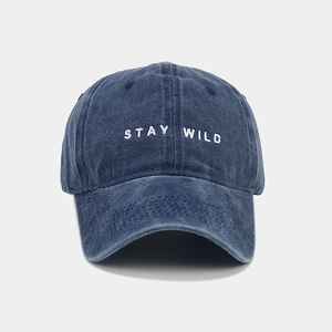 Dettaglio del ricamo 'STAY WILD' su un cappello in cotone blu scuro lavato