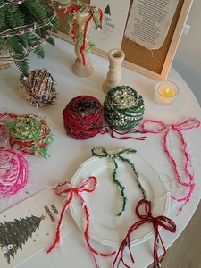 Close-up of Christmas DIY pom poms and bows on a cozy festive table setting