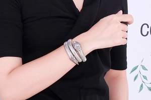 Detail shot of a silver cobra snake spiral bangle on a model's wrist with scaly texture