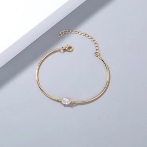 Detail view of gold metal bangle featuring an oval zircon center and adjustable clasp