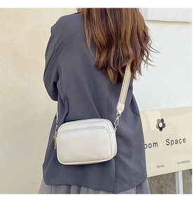Detail of a beige crossbody bag with lychee texture and adjustable wide strap
