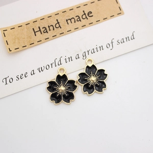 Detailed close-up of two black cherry blossom flower charms with golden edges and metal loops