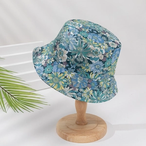Floral cotton bucket hat with colorful daisy print on a wooden stand for sun protection