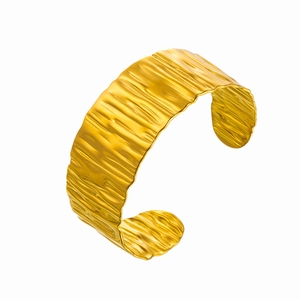 Detail of gold wave snake cuff bracelet featuring a textured hammered metal finish