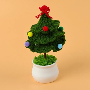 Handmade crochet Christmas tree with colorful pom-poms and red bow in a white ceramic pot