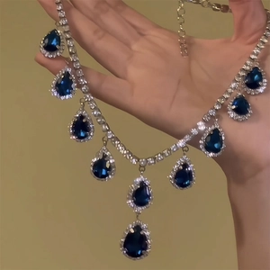Macro shot of a vintage teardrop pendant featuring deep blue gems and silver rhinestones