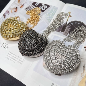 Three elegant heart-shaped crossbody evening bags with rhinestones in gold, black, and silver