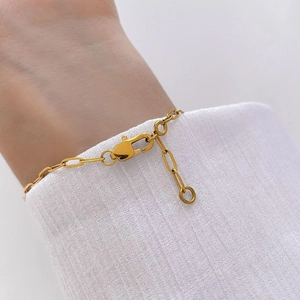 Close-up of golden hollow chain bracelet with lobster clasp on a ribbed sleeve