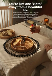 Detail of round jute placemat with black pom-poms on a rustic plaid fringed tablecloth