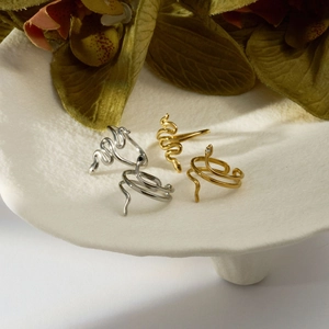 Close-up of gold and silver snake rings with enamel and diamonds on a ceramic stand