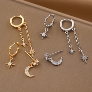 Macro view of gold and silver star moon earrings with cubic zirconia on metallic backdrop