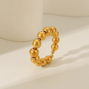 Detailed view of an 18K gold plated stainless steel beaded ring on a minimalist pedestal