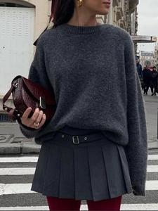 Street style view of dark gray knit sweater and pleated mini skirt with belt