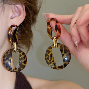 Close-up of tortoise shell acrylic hoop earrings with golden metal link and leopard print