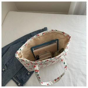 Flat lay of cream canvas tote bag with cherry print showing large capacity for essentials