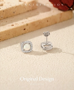 Detailed close-up of square halo stud earrings with opal stone on a textured stone base