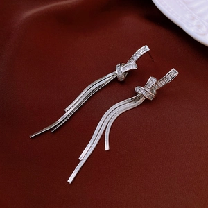 Detail of silver tassel earrings featuring a knot design and sparkling zircon stones