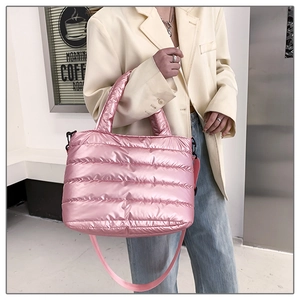 Pink quilted down-filled crossbody bag with metallic finish shown on shoulder in daily use